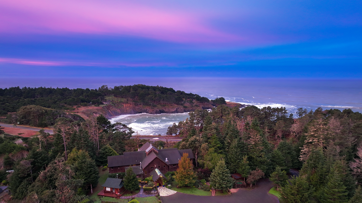 Aerial view of Brewery Gulch Inn among the pines above the Mendocino coast at sunset