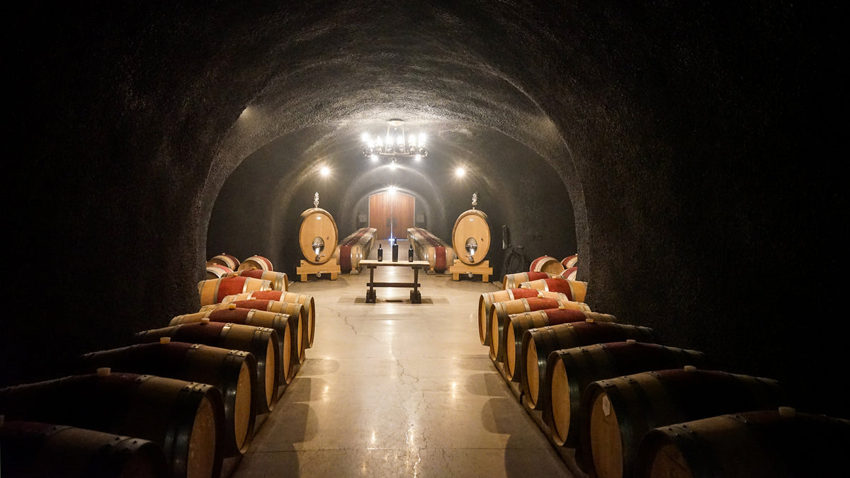 Barrel-lined cave at Cathiard Vineyard with a chandelier-lit tasting alcove at the far end, Napa Valley