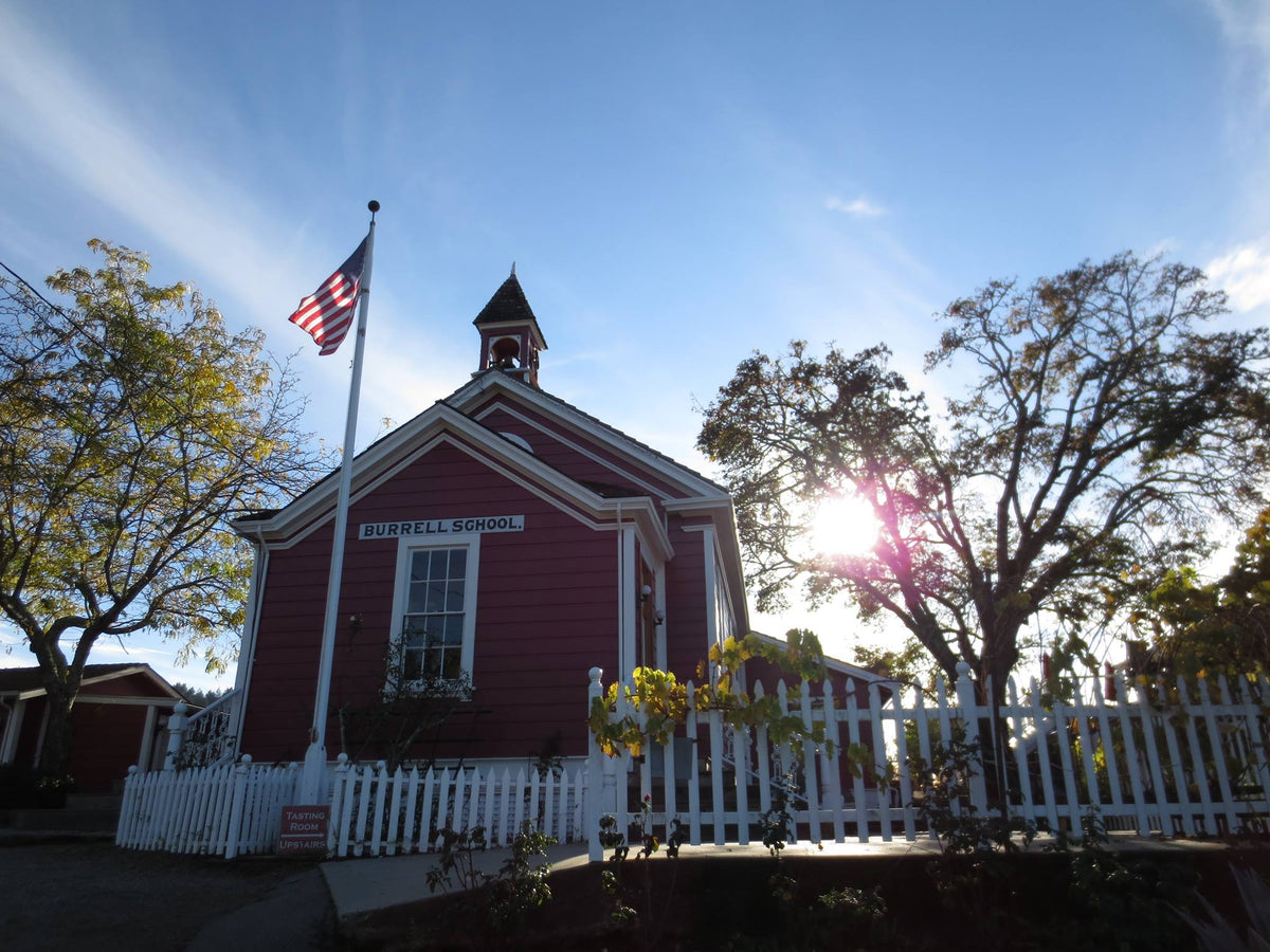 The red schoolhouse tasting room of Burrell School Vineyards with its bell tower and picket fence, Santa Cruz Mountains