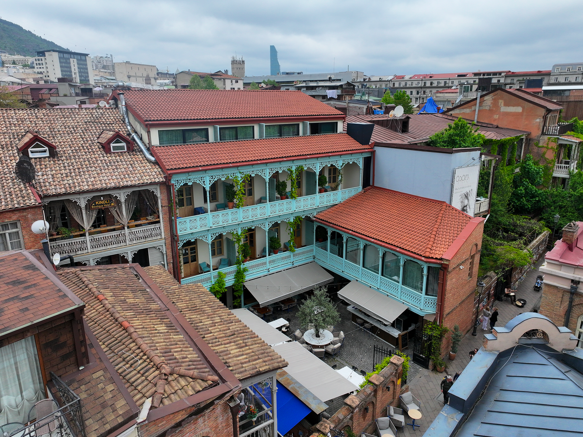 Aerial view of The Blue Fox Hotel's tiered turquoise balconies and courtyard among Tbilisi's tin roofs