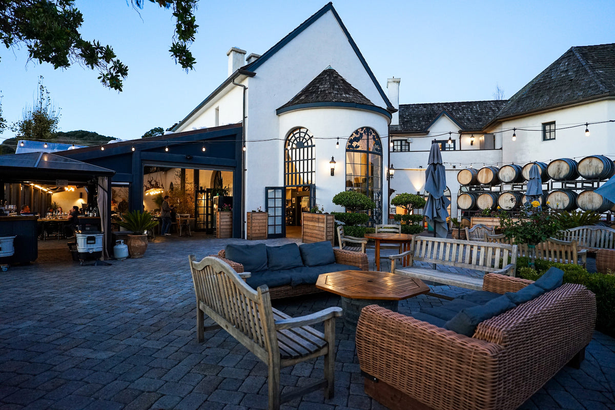 The courtyard lounge, string lights and barrel-lined patio of Folktale Winery at dusk, Carmel Valley
