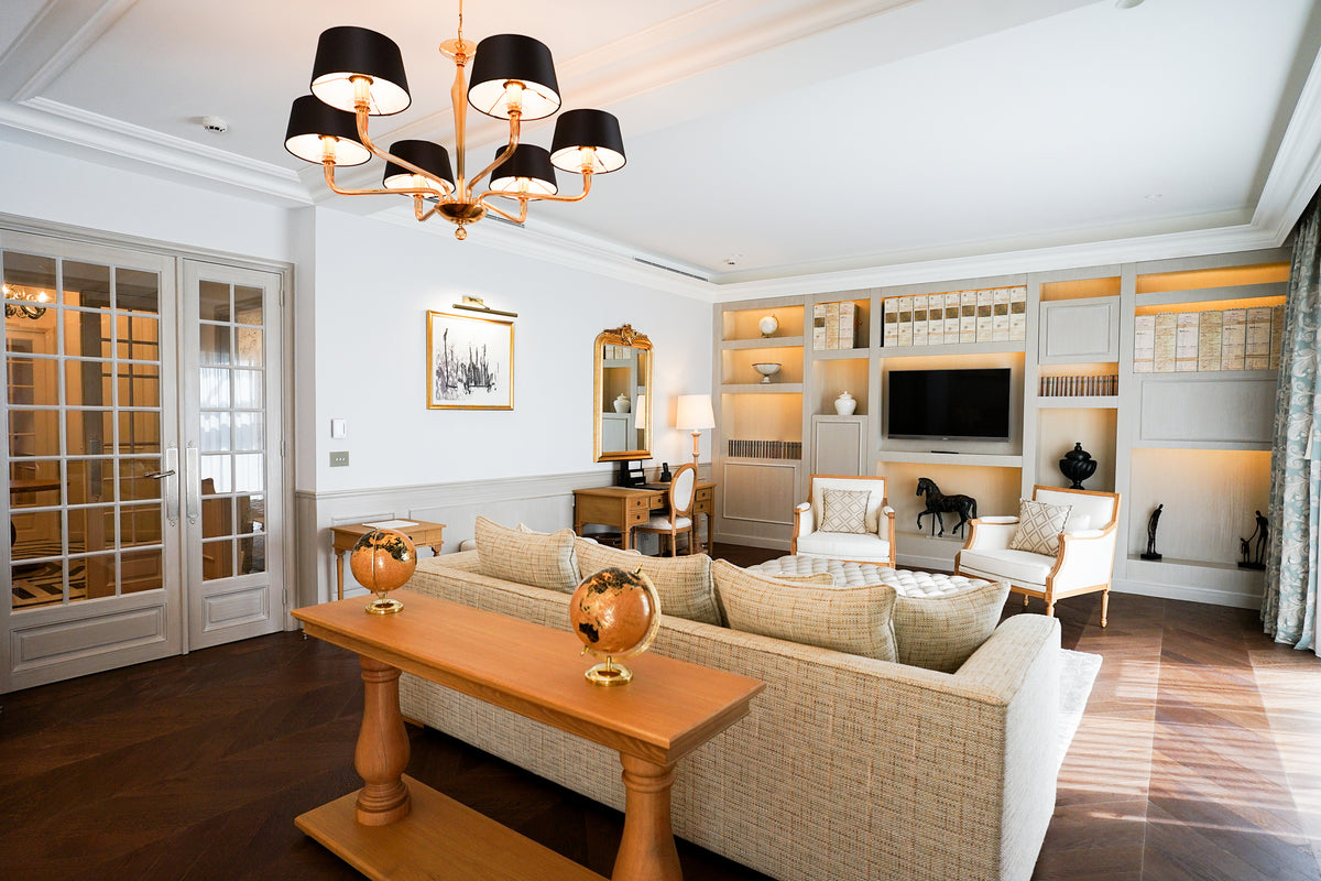 Suite living room with a chandelier, bookshelves and cream sofas at Hôtel Chais Monnet, Cognac
