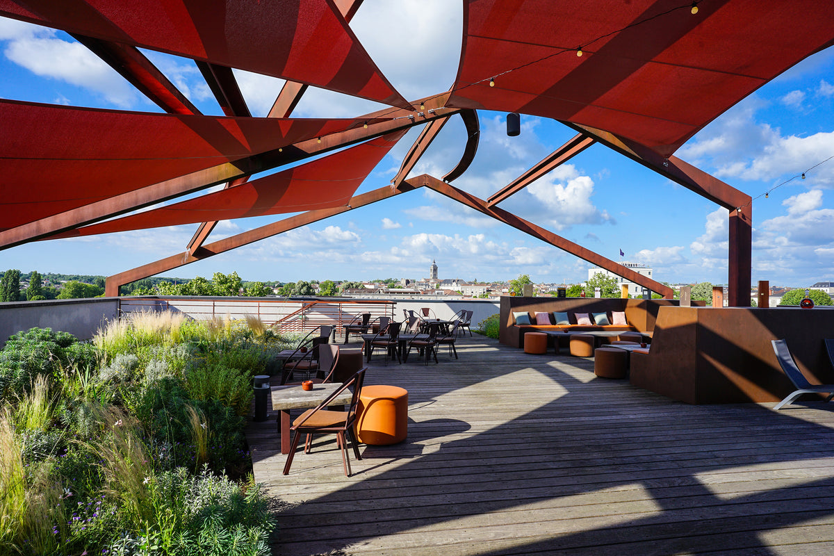 Rooftop bar terrace under a red lattice canopy overlooking the town of Cognac at Hôtel Chais Monnet