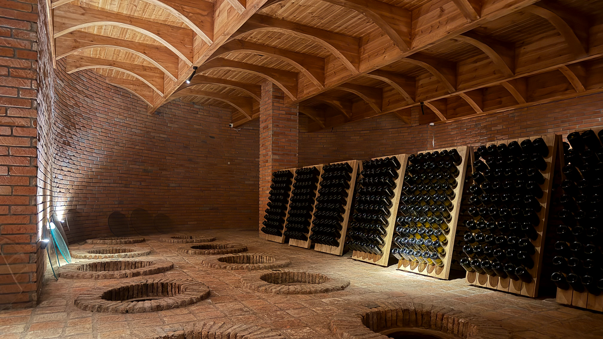 Buried qvevri and stacked bottles under the brick-vaulted cellar ceiling at Château Buera, Lopota, Kakheti