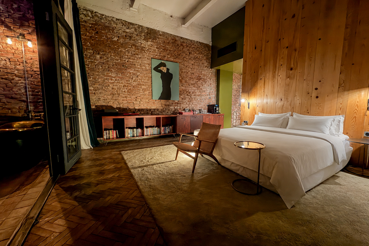 Loft-style guest room with exposed brick, a wood-panelled wall and a bookshelf at Stamba Hotel, Tbilisi