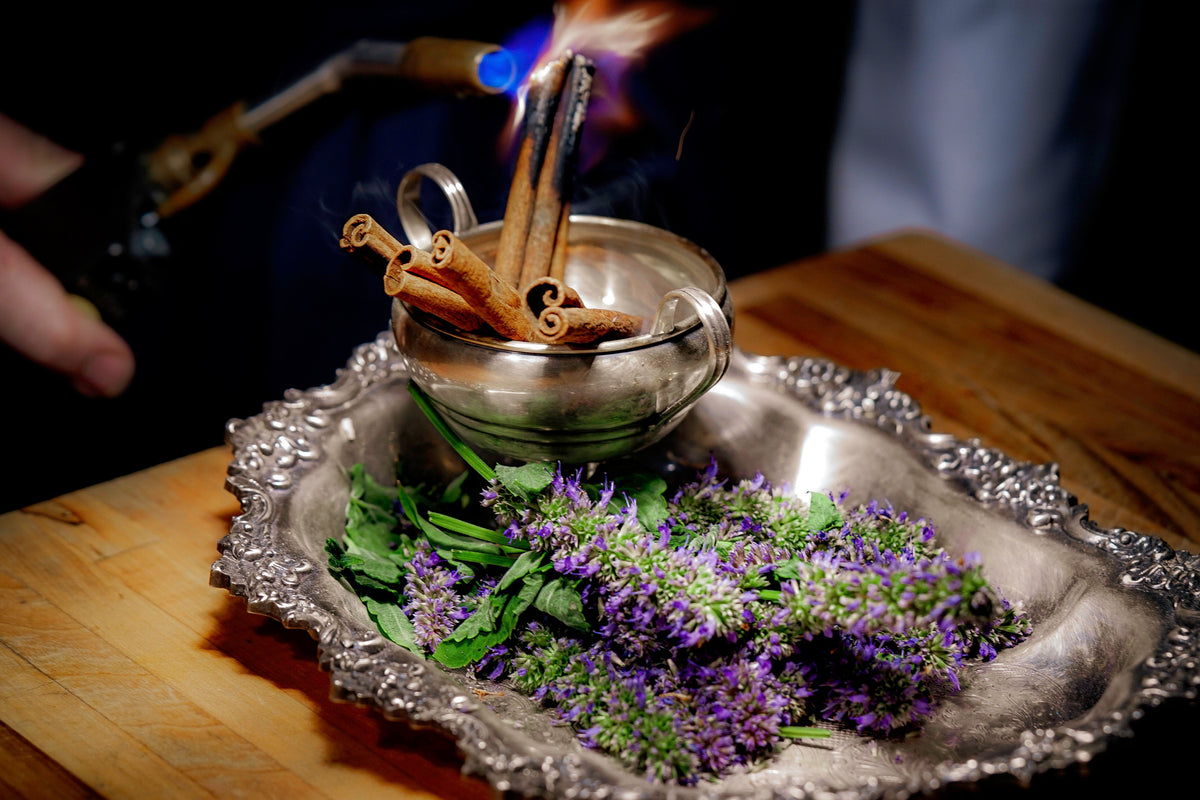 A server torching cinnamon sticks over a silver tray of lavender at Troubadour, Healdsburg