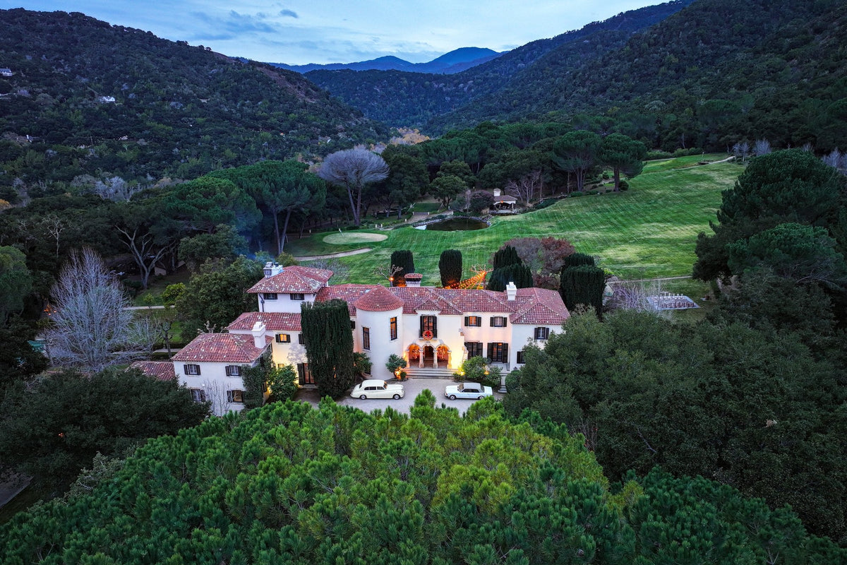 Aerial view of the white Stonepine Estate mansion and its lawns in the oak-covered hills of Carmel Valley