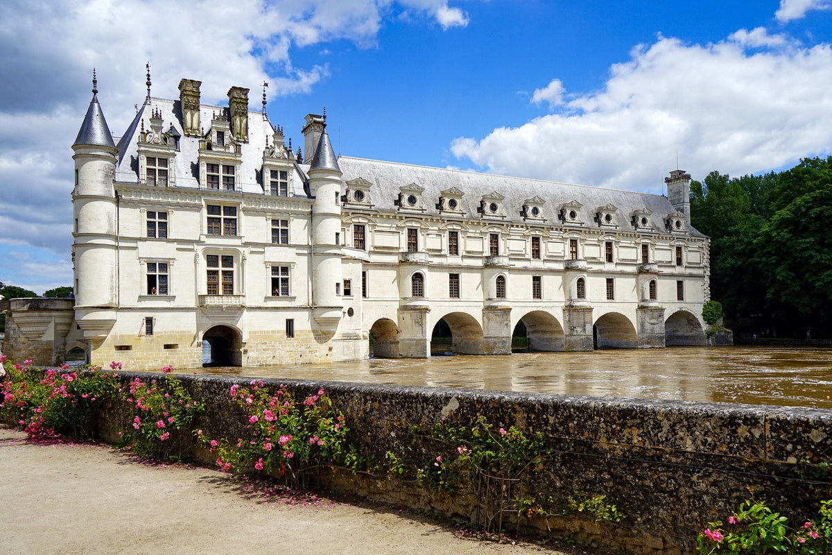 Château de Chenonceau spanning the River Cher on its arched gallery, with rose beds in the foreground, Loire Valley